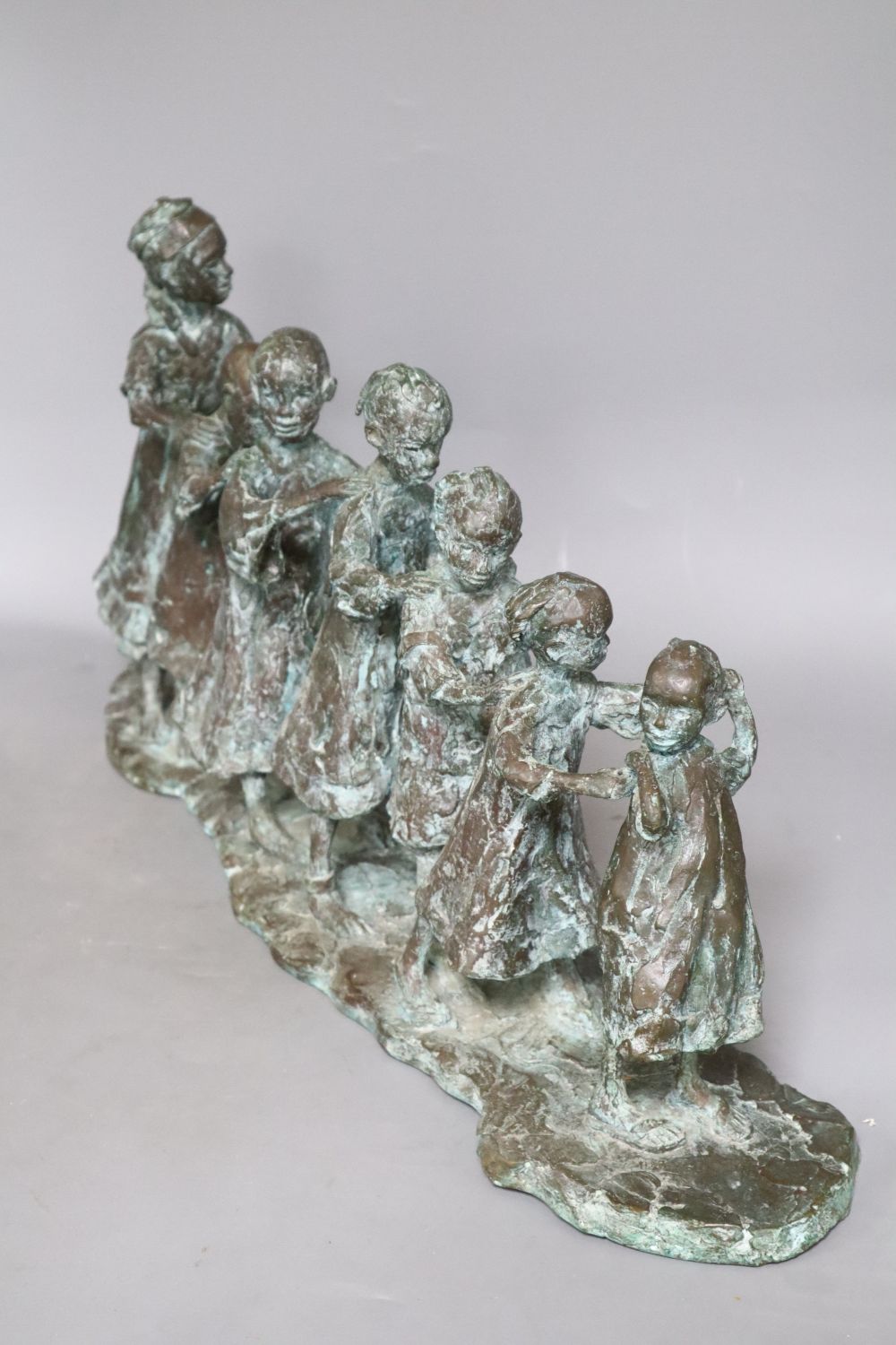 Lucy Poett (b.1942). A bronze of Seven South children in a line, signed, height 29cm width 58cm